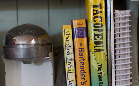 Row of cookbooks next to salt shaker.