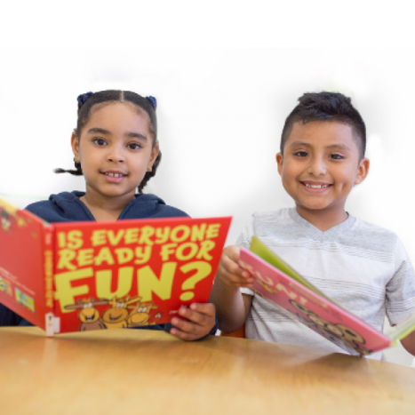 Photograph of two children sitting next to each other and smiling with open books
